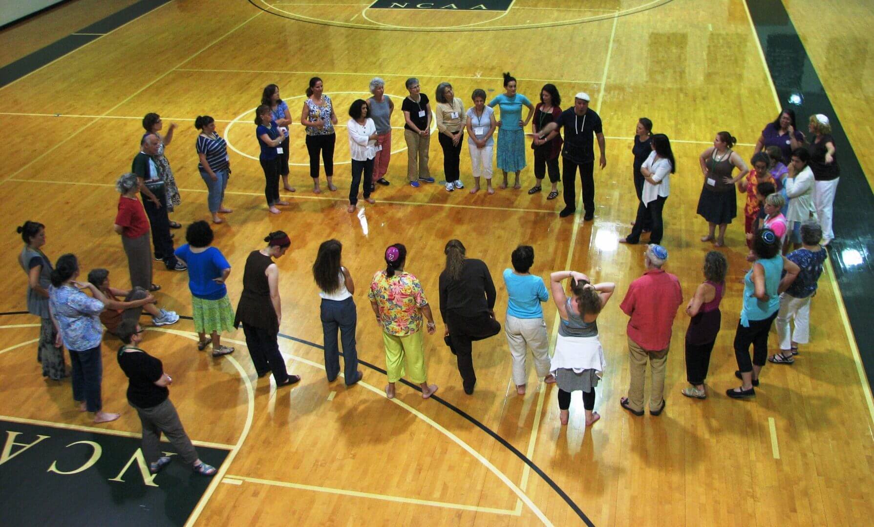 Educators standing in a circle in a gym for an activity