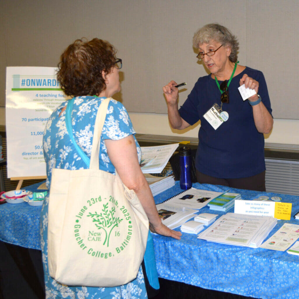 Educators chatting at an exhibitor table at NewCAJE
