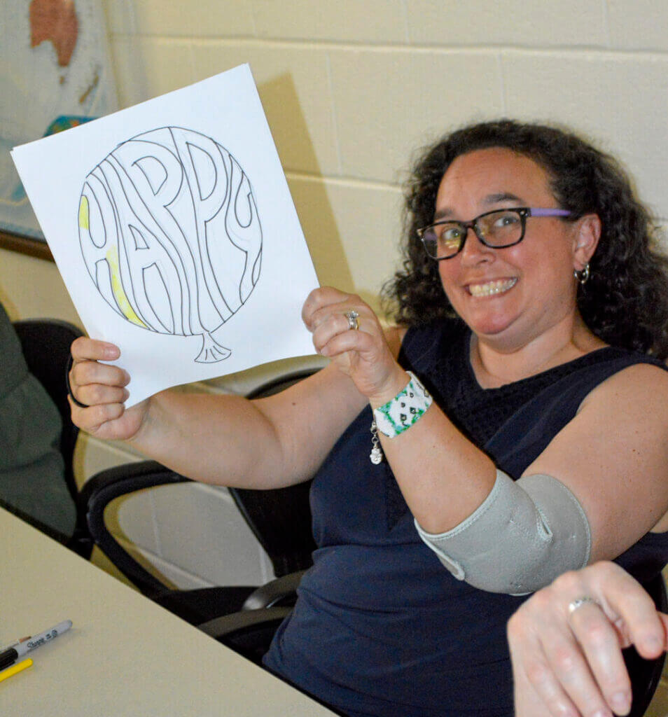 Woman holding up a hand-drawn design at a workshop