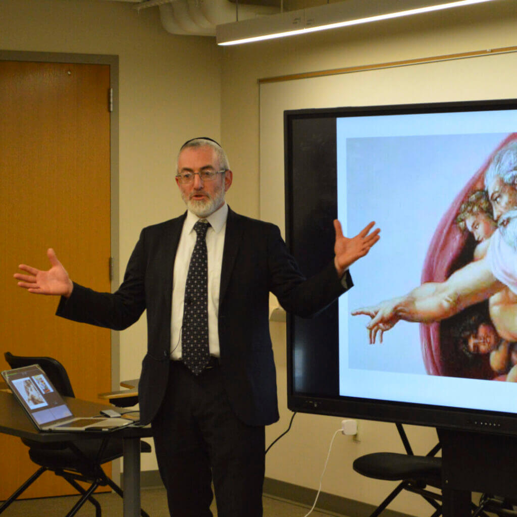 Presenter in a suit speaking beside a projected slide