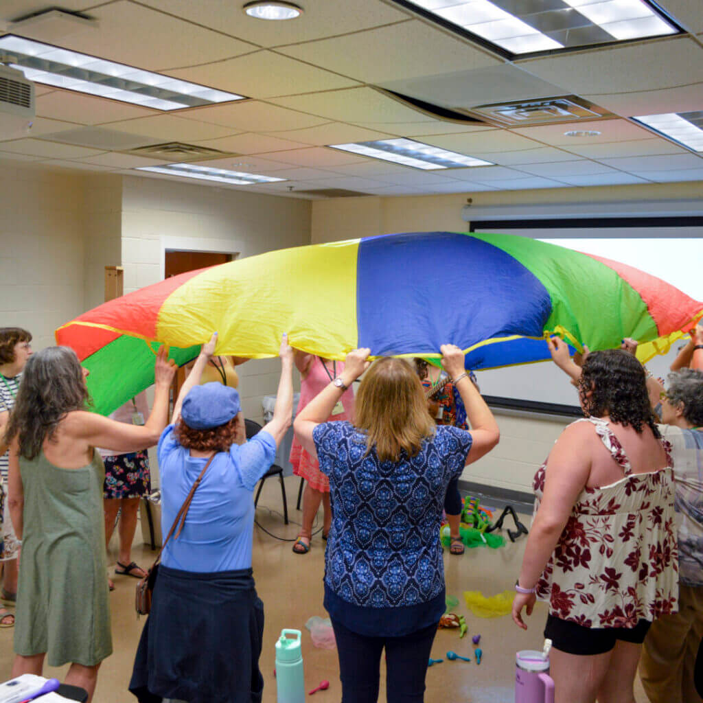 Educators playing under a colorful parachute