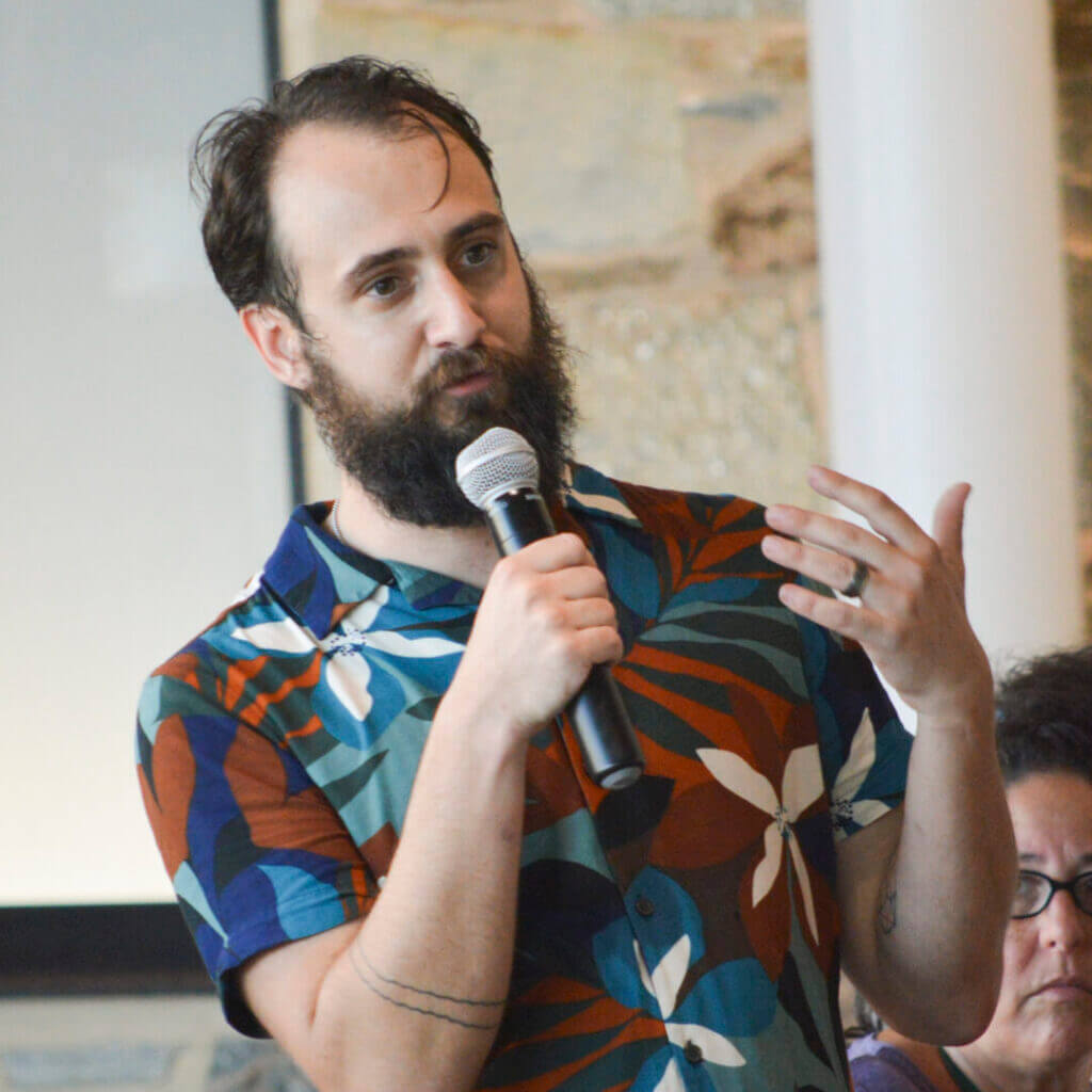 Bearded man speaking into a microphone