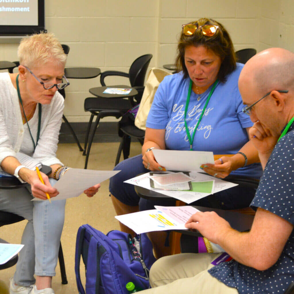Teachers working together on papers at a session