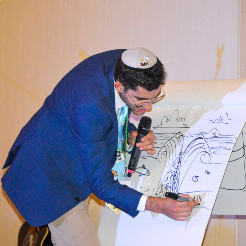 Man in a kippah drawing on a large sketch pad